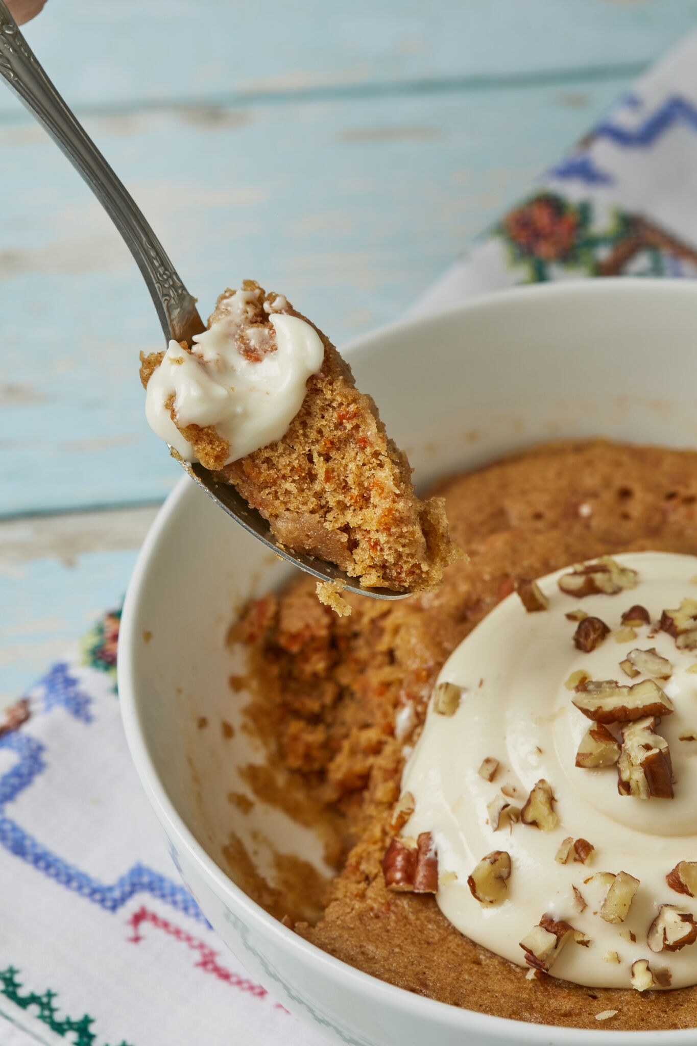 A spoonful of delicious carrot cake from the bowl, paired with tangy creamy cream cheese frosting and crunchy toasted walnuts and pecans. 