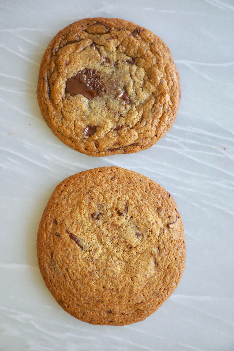 Two chocolate chip cookies, one had been flattened while the other did not.