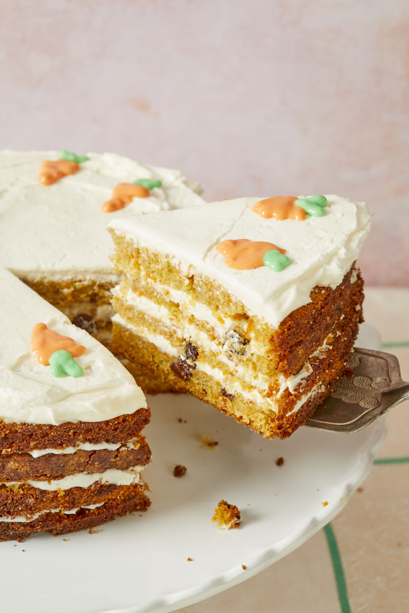 Layered Carrot Cake loaded with raisins and carrots, topped with creamy cream cheese frosting. A slice is cut and ready to serve. 