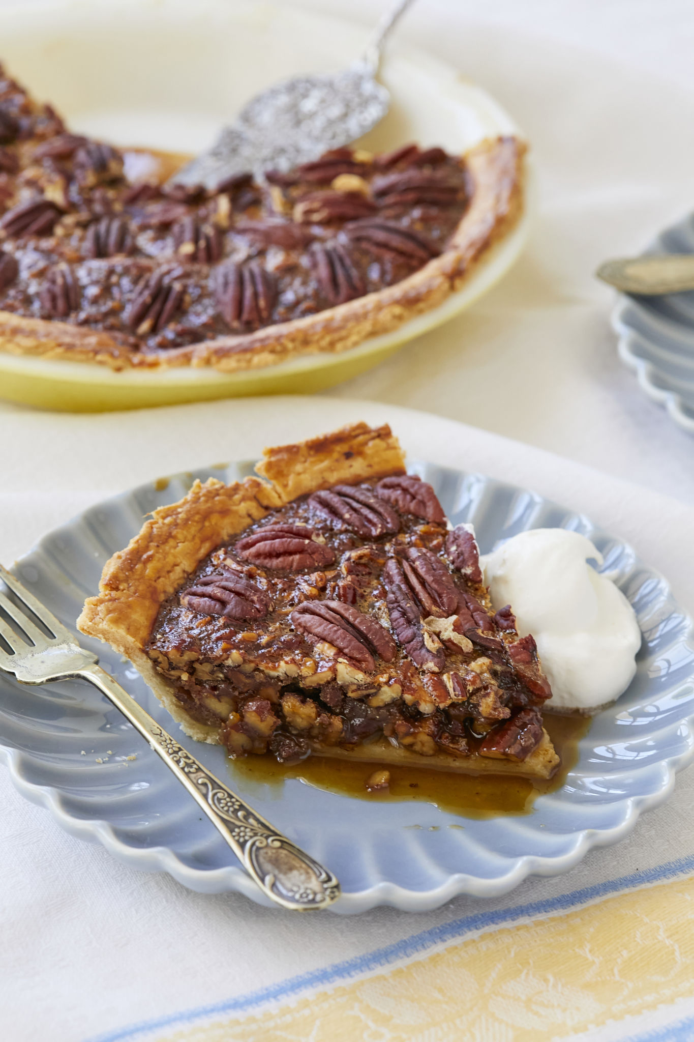 A close up image of a slice of homemade pecan pie shows toasted pecans on top and the caramel center.