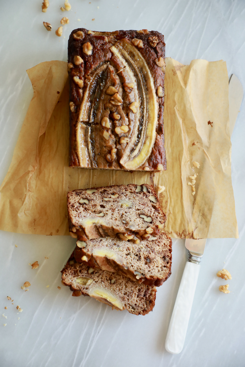 Gluten-free banana bread, topped with slices of banana, sliced.