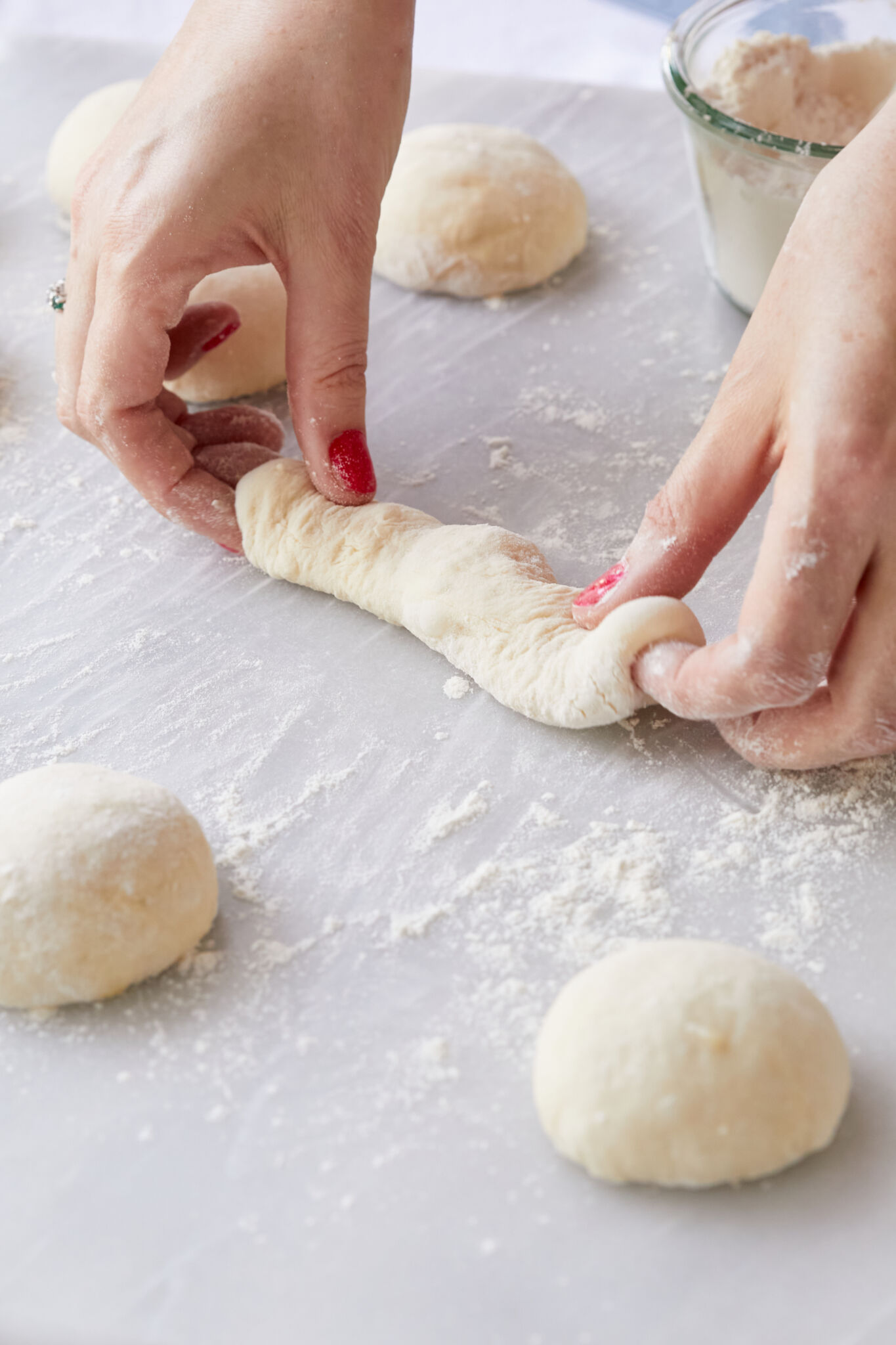 Step-by-step instructions on how to make Garlic Breadsticks: Roll individual balls into logs on a slightly floured surface, preparing for baking. 