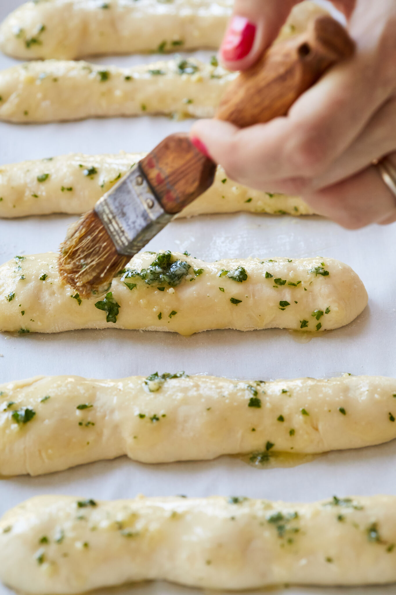 Brush the mixture of melted butter, garlic, and parsley on the doubled-in-size dough before baking. 