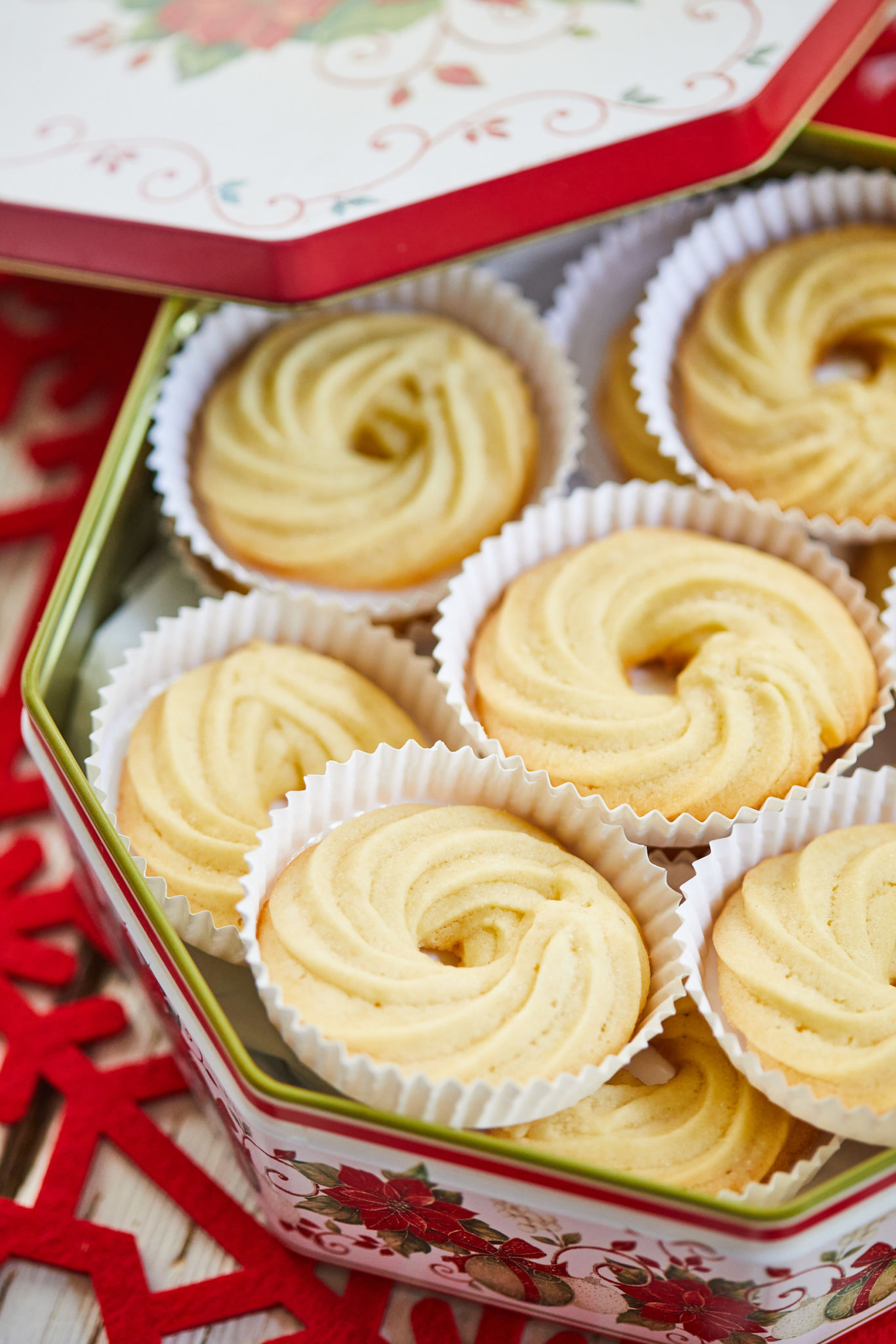 Festive Danish Butter Cookies are stored in cupcake liners in a red and white Christmas-themed metal tin. Danish cookies are baked until lightly golden with slight crisp on the outside. 