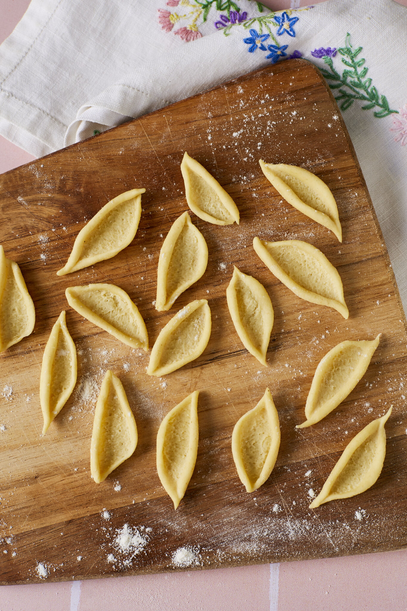 Olive Leaf Pasta is placed on a lightly floured wood board. Foglie d'Ulivo is in elongated, shell-like shape which is big enough to work in a variety of dishes and perfect for capturing every bite of sauce.