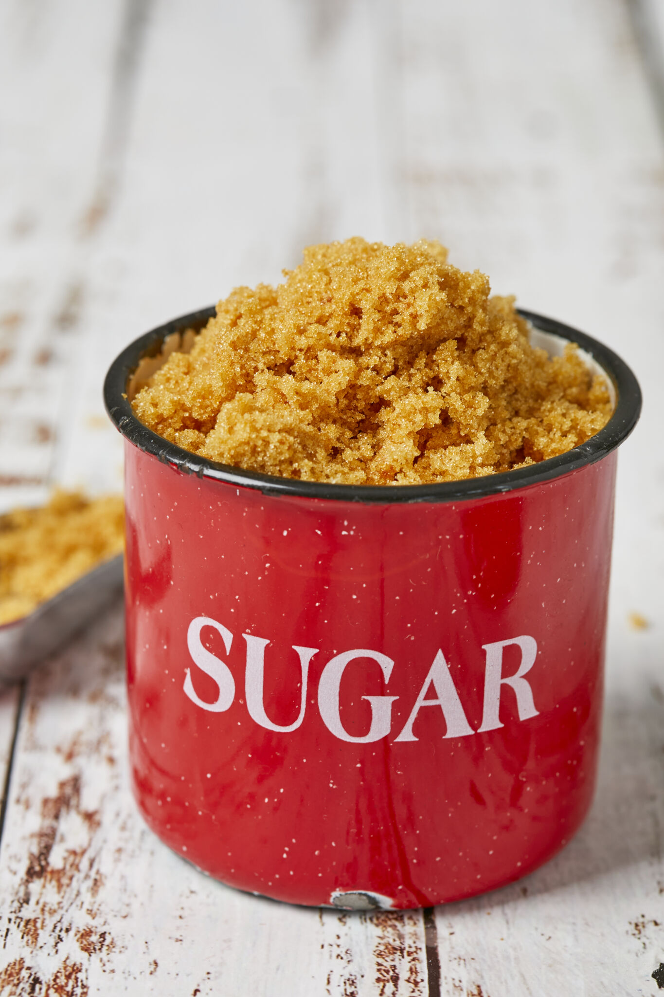 Homemade Brown Sugar is stored in a red enamel mug with white speckles all around and "sugar" on the front. 