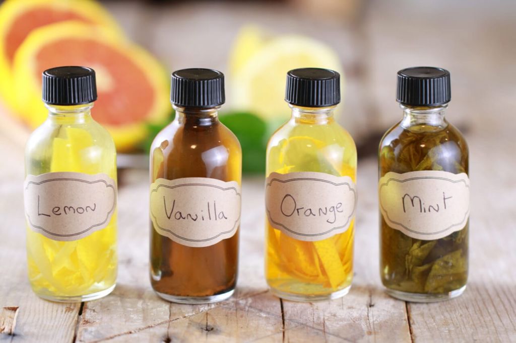 Four bottles of homemade extracts: lemon, vanilla, orange, and mint.
