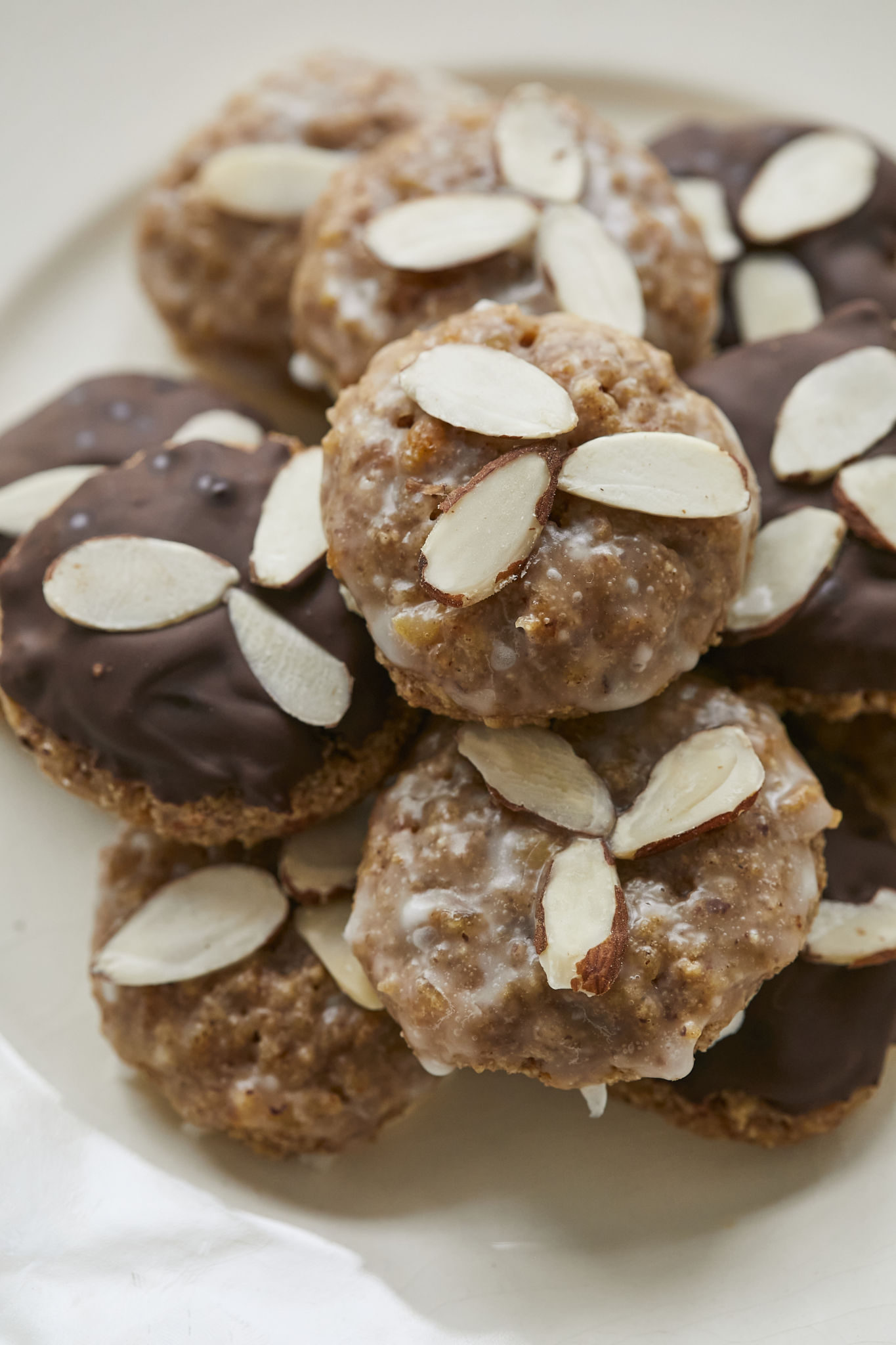 A closeup photo of Lebkuchen show the nutty texture of the cookie dough. The cookies are covered in both a vanilla and chocolate glaze and topped with almonds.