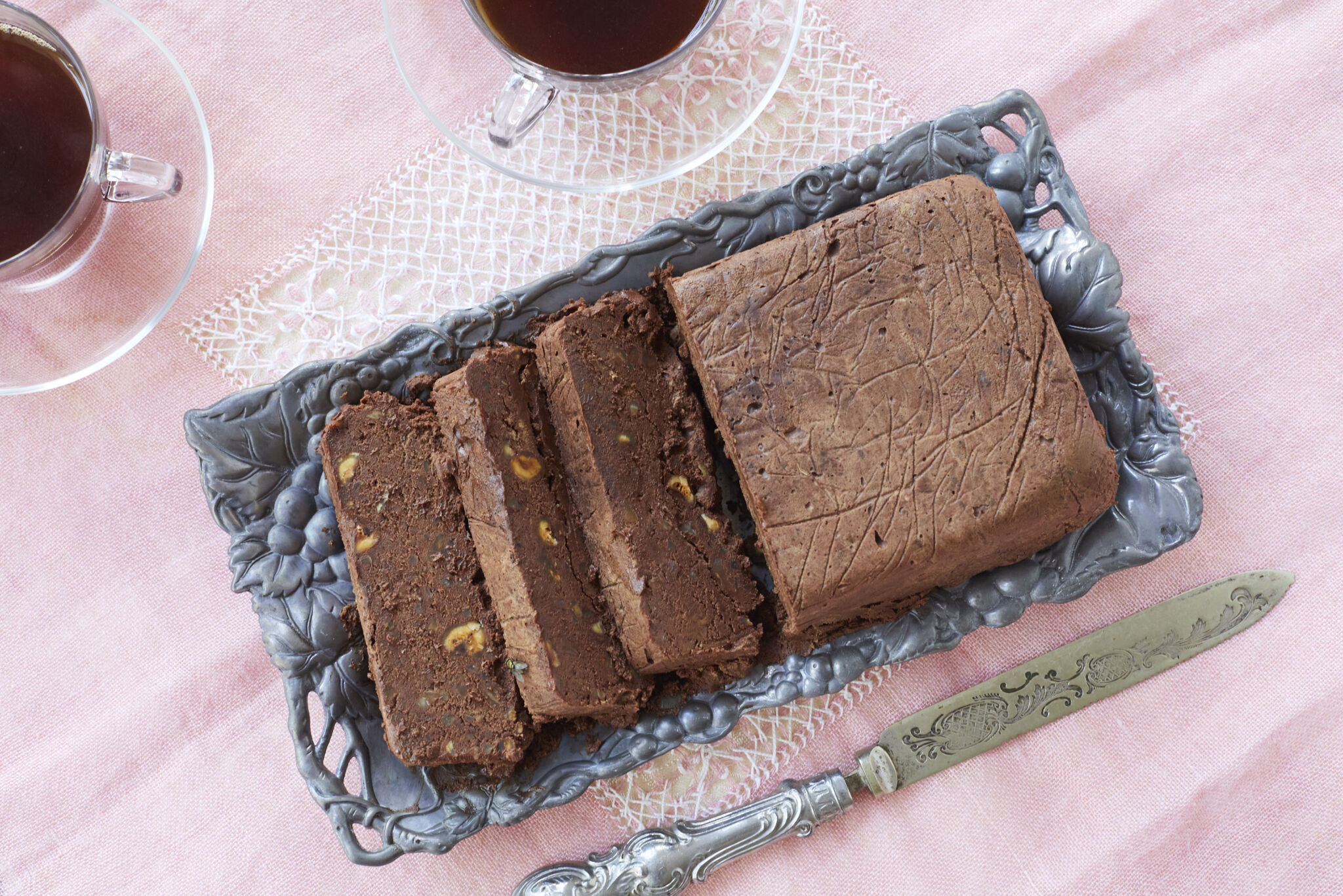 Mocha Pâté is sliced and served on a tray with two glass cups of coffee. It's a cross between rich fudge and velvety mousse, and studded with toasted hazelnuts that perfectly set off the dessert's lush texture.