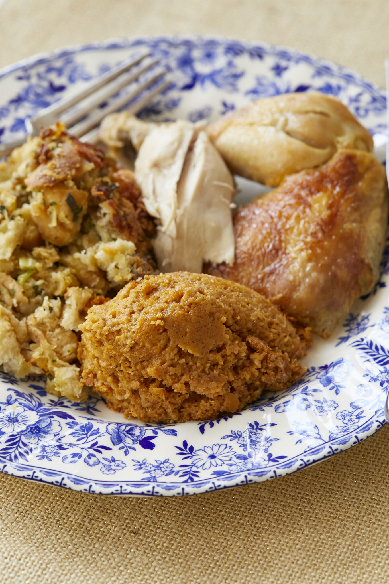 Sweet Potato Soufflé is served on a floral dinner plate with stuffing and turkey. 